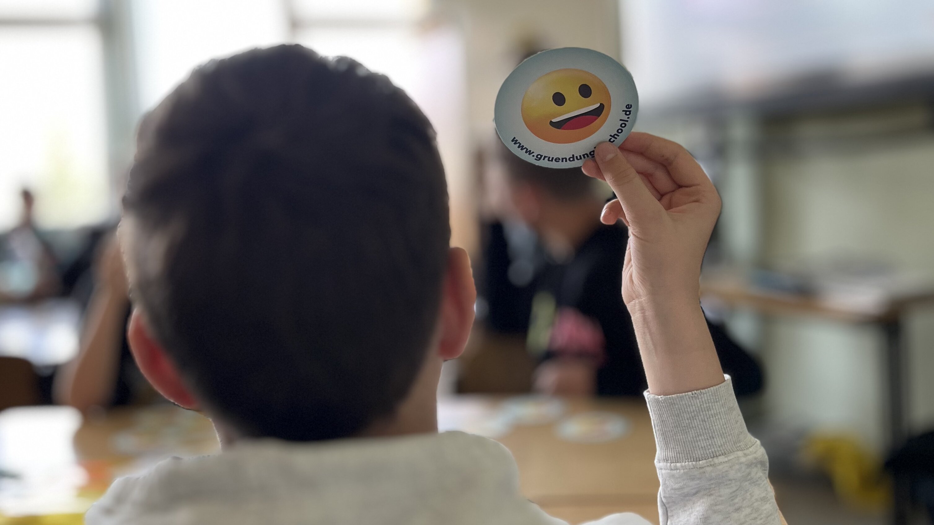 Schüler hält Karte mit Smiley hoch