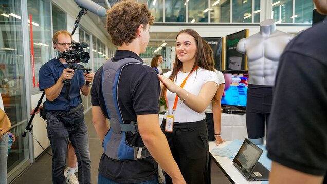 Schülerin von RighBack führt smarte Rückenorthese an jungem Mann vor
